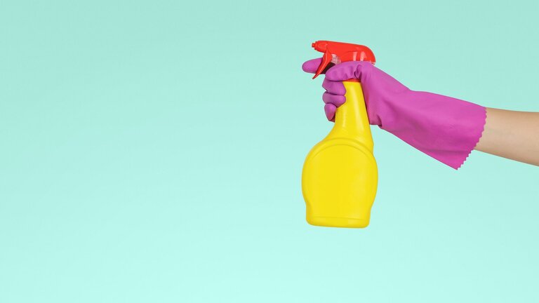 Eine mit Gummihandschuhe überzogene Hand hält eine Sprüfhflasche auf  | © unsplash