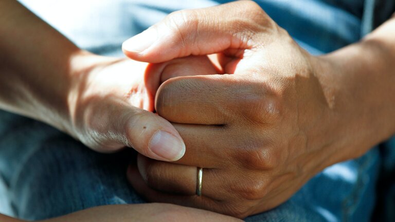 Eine Pflegeperson hält die Hände einer sterbenden Person. | © unsplash