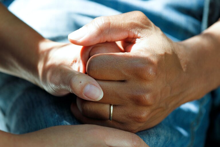 Eine Pflegeperson hält die Hände einer sterbenden Person. | © Unsplash