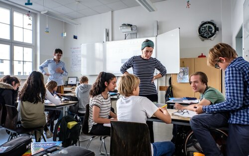 Un élève en fauteuil roulant dans une école inclusive parle avec d'autres élèves et un enseignant. | © Andi Weiland, Gesellschaftsbilder.de