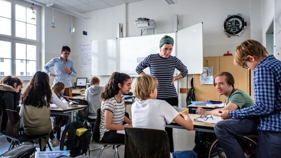 Ein Schüler im Rollstuhl an einer inklusiven Schule spricht mit anderen Schüler:innen und einer Lehrerin. | © Andi Weiland, Gesellschaftsbilder.de