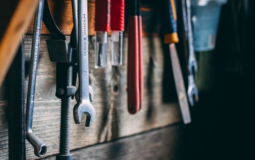 Werkzeuge hängen an einer Holzwand. | © unsplash