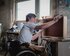 Ein junger Mann im Rollstuhl bearbeitet in einer Werkstatt ein Stück Holz, aus dem wohl ein Schrank wird. | © Andi Weiland/ Gesellschaftsbilder.de