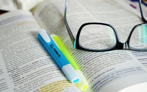 Foto einer Brille, die zusammen mit Markern auf einem Stapel Büchern liegt. | © Hans/Pixabay