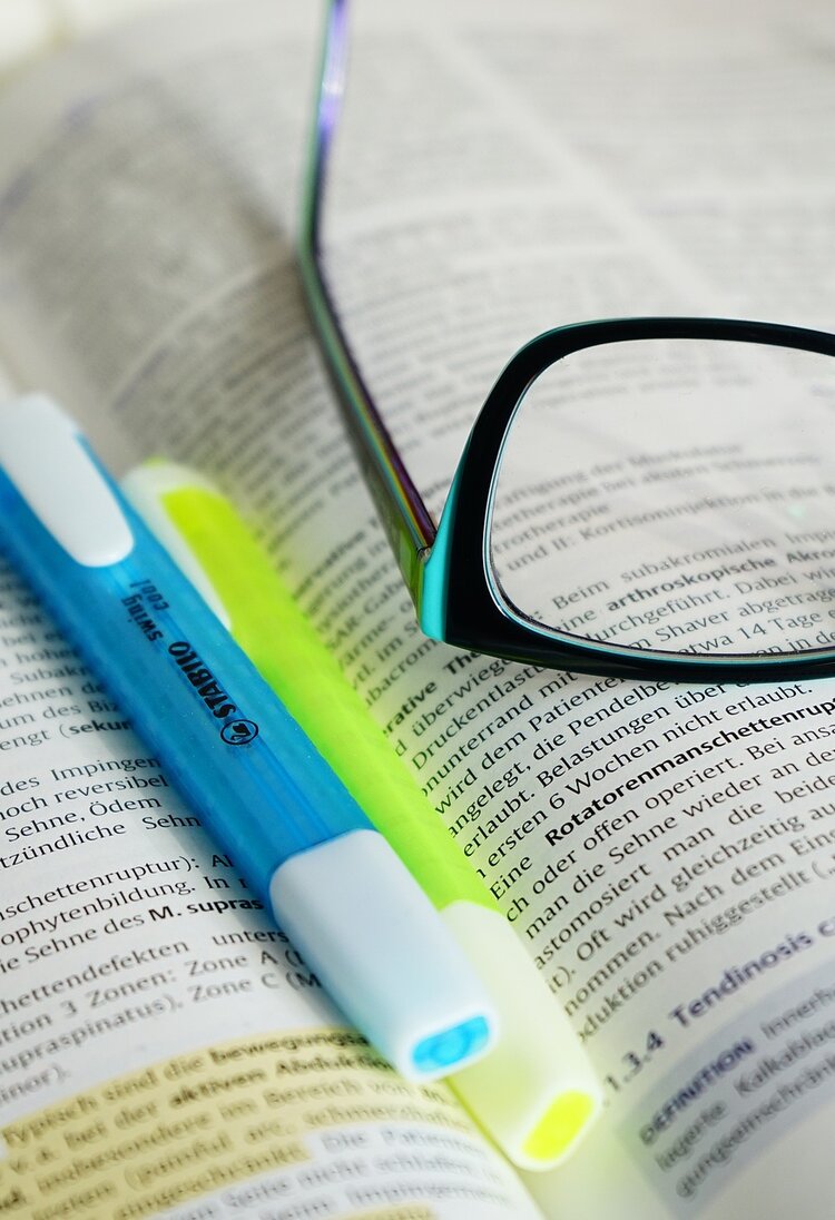 Foto einer Brille, die zusammen mit Markern auf einem Stapel Büchern liegt. | © Hans/Pixabay