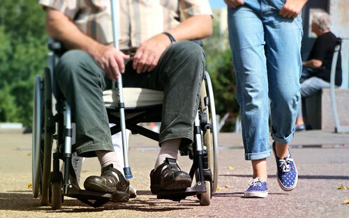 Homme en fauteuil roulant, femme marchant à côté.  | © pixabay