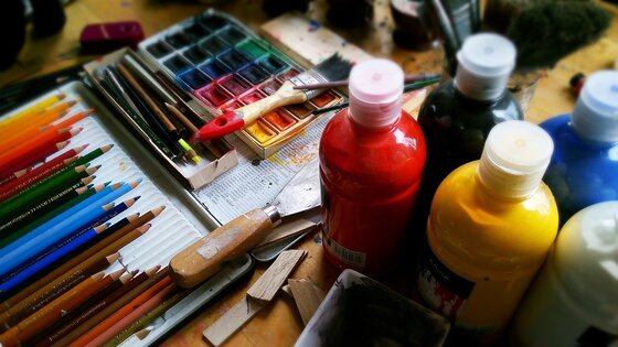Künstlerequipment wie Farben und Pinsel auf einem Tisch. | © Pixabay