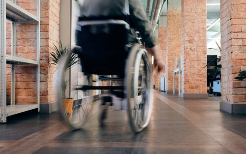Le fauteuil roulant se déplace rapidement dans un bureau. La personne en fauteuil roulant n'est pas reconnaissable. | © Pexels / Marcus Aurelius