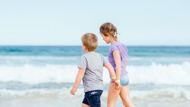 Zwei Kinder laufen Händchen haltend am Strand. | © Unsplash