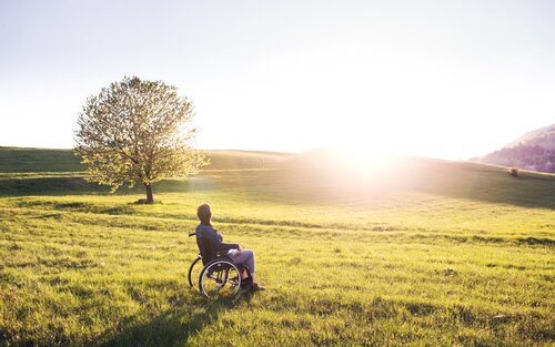 Frau im Rollstuhl schaut in den Sonnenaufgang. | © pexels