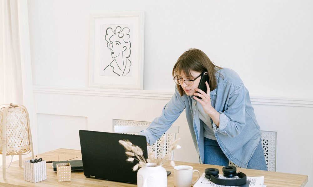Eine Frau telefoniert mit dem Handy und schaut gleichzeitig etwas im Laptop nach. | © pexels