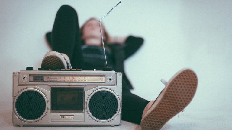 Junge, der auf dem Boden liegt und seinen Fuss auf einen CD-Player gelegt hat | © unsplash