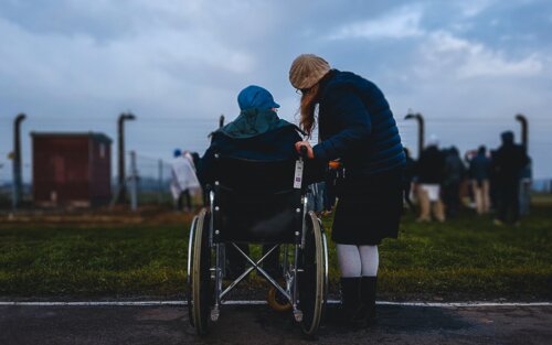 Mann im Rollstuhl und danebenstehende Frau von hinten fotografiert | © unsplash