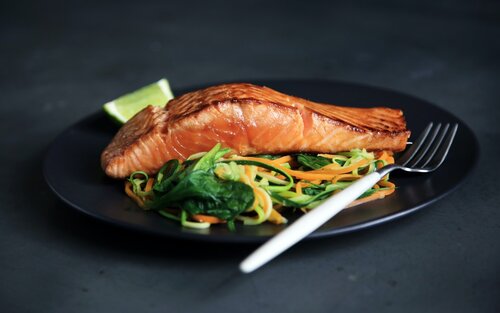 Auf einem schwarzen Teller liegt Lachs mit Gemüse und eine Gabel.  | © unsplash