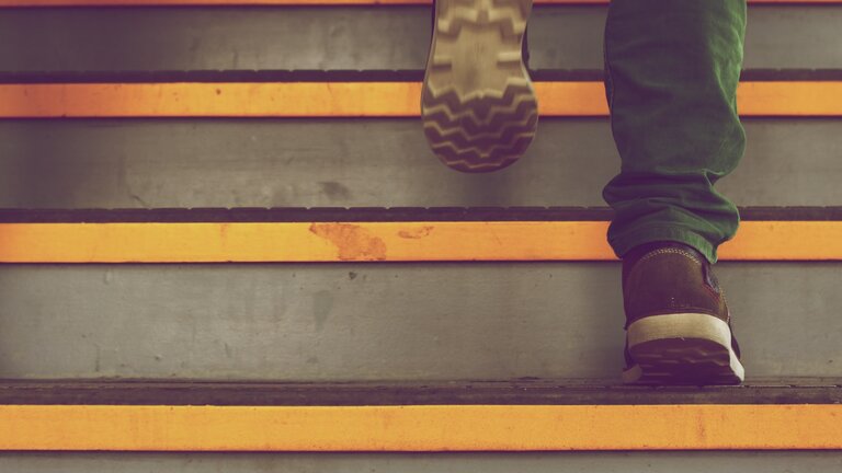 Man sieht Füsse, die eine Treppe hochsteigen. | © Unsplash