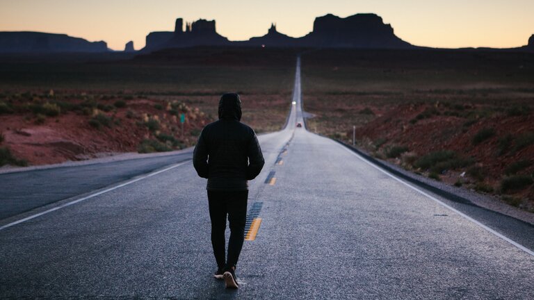 Eine Frau läuft alleine auf einer grossen Strasse.  | © unsplash