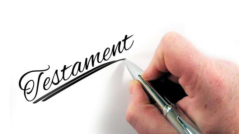 Eine Hand, die "Testament" auf einen Zettel schreibt. | © Pixabay
