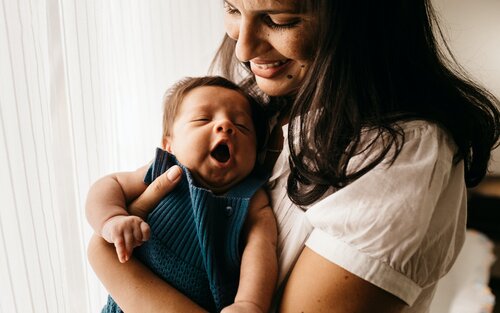 Eine Mutter hält lächelnd ihr Baby im Arm. | © unsplash