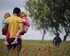 Ein Vater trägt seine zwei kleinen Kinder und läuft mit ihnen auf einem Blumenfeld.  | © unsplash