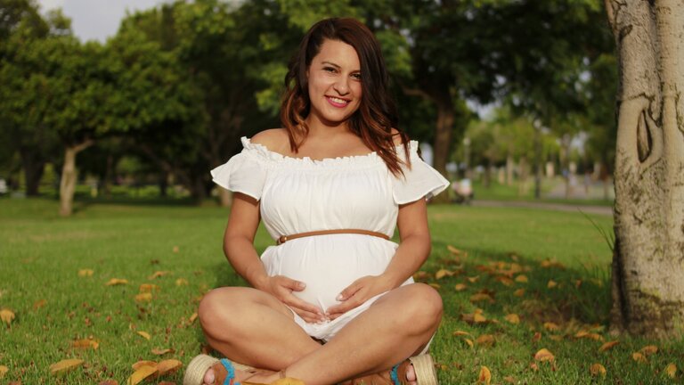 Eine schwangere Frau sitzt auf Gras.  | © Unsplash