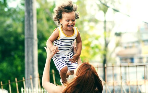 Eine Mutter wirft ihr lachendes Kind in die Luft. | © unsplash