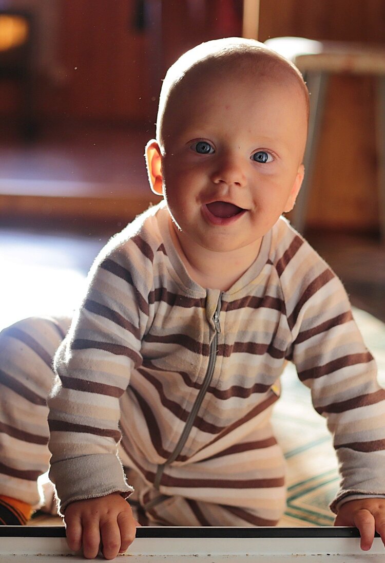 Ein Baby im Strampler krabbelt und lächelt in die Kamera. | © Pixabay