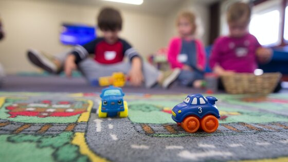 Kinder spielen auf einem Kinderteppich mit Spielzeugautos.  | © Unsplash