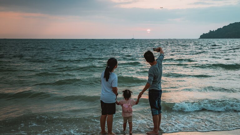 Eine dreiköpfige Familie macht ein Foto von sich am Strand. | © Pixabay