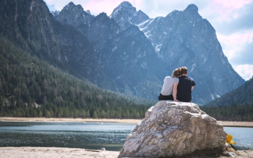 Ein Paar sitzt an einem See auf einem Felsen. | © unsplash