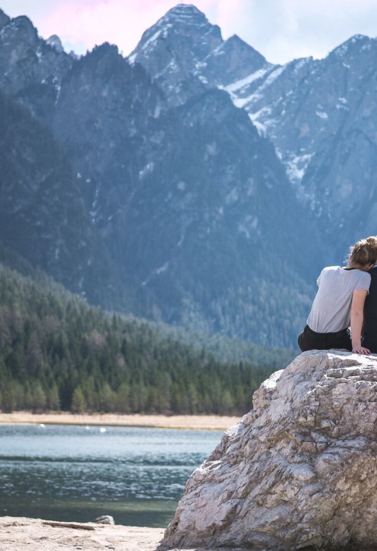 Ein Paar sitzt an einem See auf einem Felsen. | © Unsplash