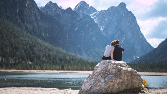 Ein Paar sitzt an einem See auf einem Felsen. | © Unsplash