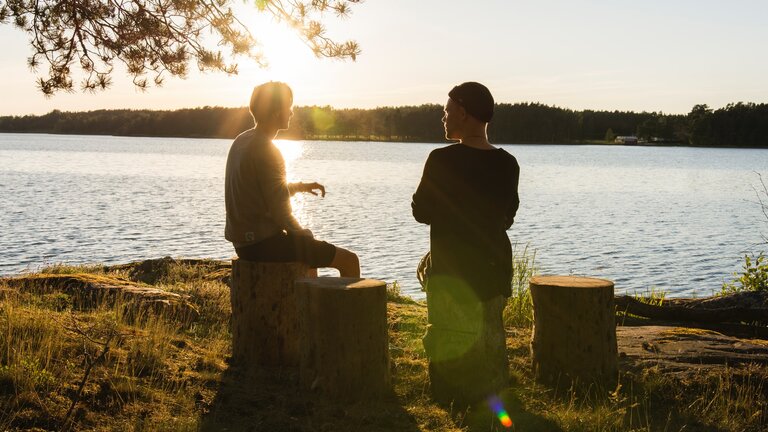 Deux pères ont une conversation détendue au bord d'un lac. | © unsplash