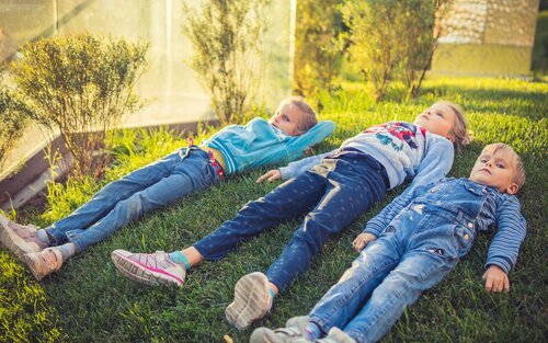 Trois enfants sont allongés dans une prairie. | © unsplash