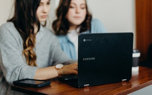 Zwei junge Frauen sitzen vor einem Laptop. | © unsplash