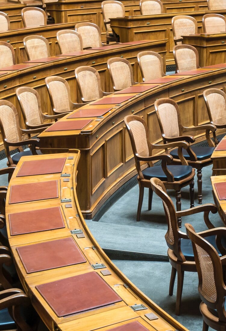 Bild des Nationalraatssaals mit leeren Stühlen. | © Unsplash / Hansjörg Keller