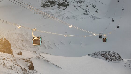 Les cabines du téléphérique "Matterhorn glacier ride" au-dessus des parois rocheuses enneigées. | © SBB CFF FFS