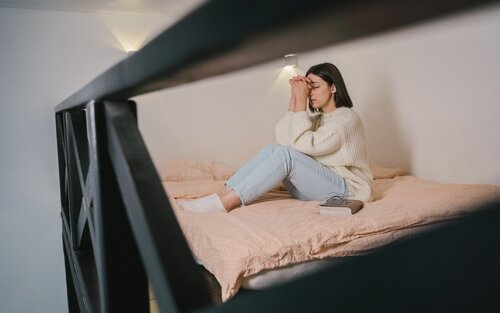 Eine Frau sitzt nachdenklich auf ihrem Bett. | © pexels
