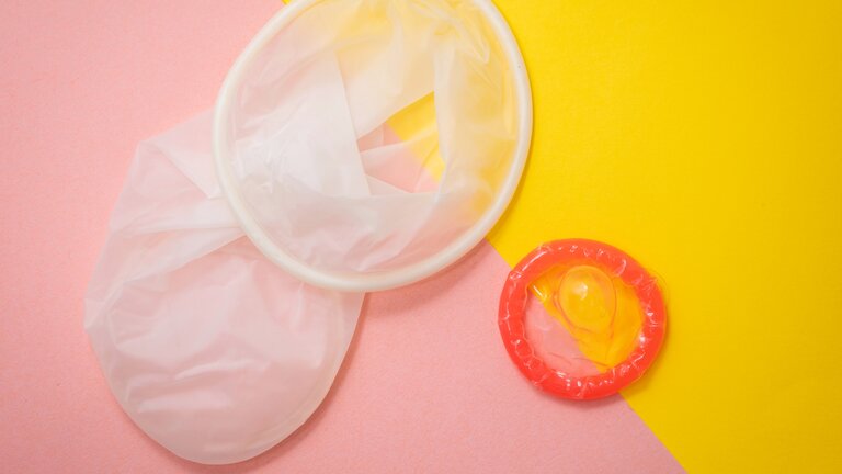 Ein Kondom sowie ein Frauenkondom vor gelb-rosa Hintergrund. | © unsplash