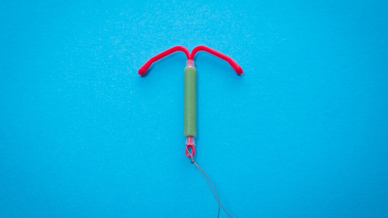 Eine rot-grüne Hormonspirale vor blauem Hintergrund. | © unsplash