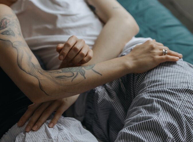 Nahaufnahme von zwei Personen, die gemeinsam auf einem Bett liegen und sich gegenseitig am Bein berühren. | © pexels