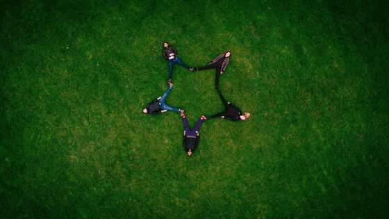 Cinq adultes s'allongent sur l'herbe et forment une étoile. | © Pixabay