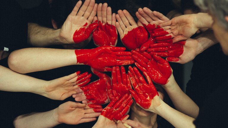 Cœur rouge peint sur de nombreuses mains. | © unsplash