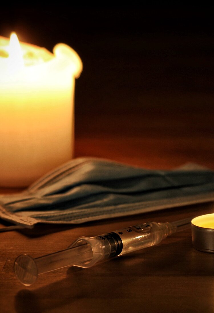 Kerzen beleuchten eine Maske und eine Spritze | © pixabay
