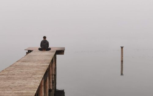 Ein Mann sitzt meditierend auf einem Steg am Meer. | © pixabay