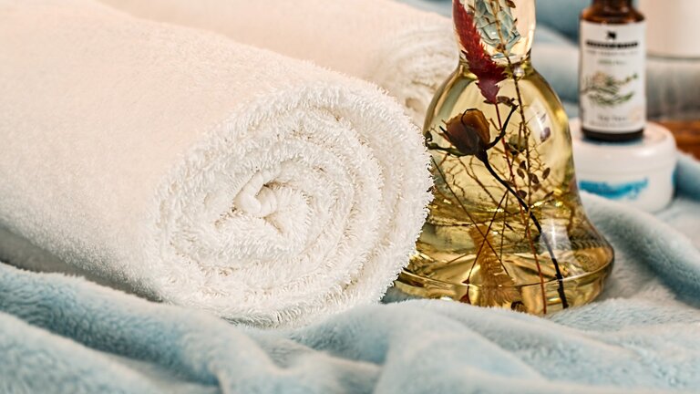 Ein Handtuch und eine Flasche Massageöl | © pixabay