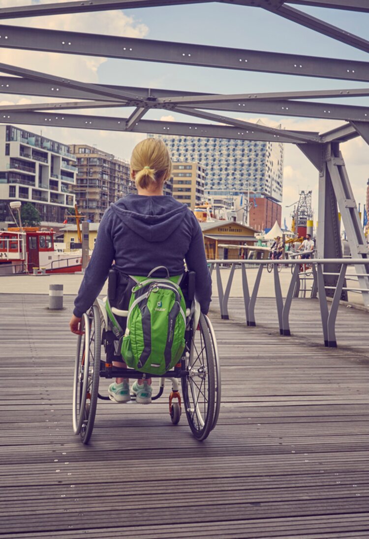 Frau im Rollstuhl, die eine Brücke überquert | © gesellschaftsbilder